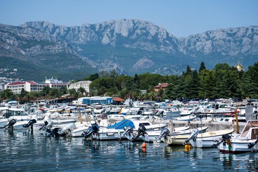Yachts port in Montenegro with mountains and city view in adriatic sea. Boats pier in sunny day with beautiful Mediterranean nature