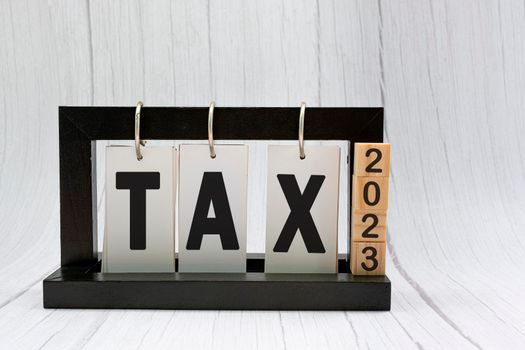 Tax text on paper stand black frame with wooden blocks on white wooden background. Property tax and tax time concept