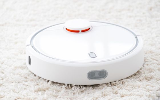 Wireless robot vacuum cleaner on white rug