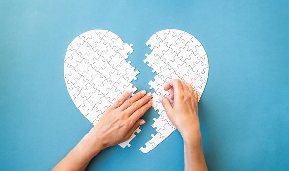 White puzzle in heart shape. White details of puzzle on blue background.