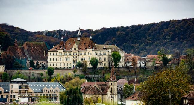 Ancient Sighisoara city in Romania, panoramic old clock tower, castle and medieval architecture view. Historic european town with Dracula house