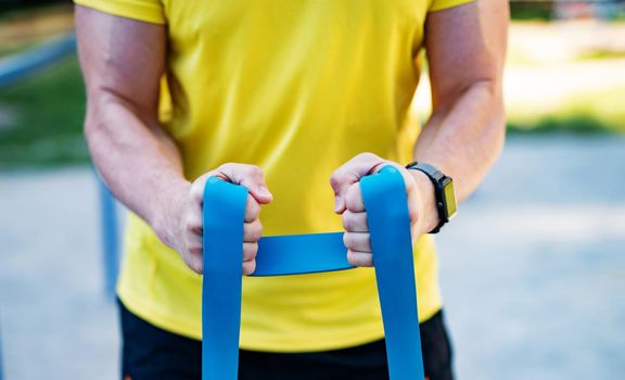 Man working out with resistance rubber bands in street, close up