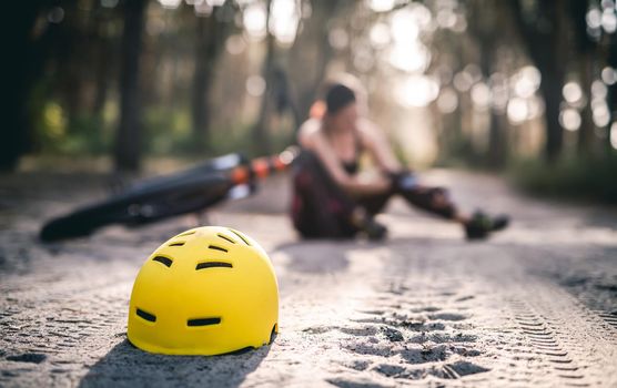 Protective helmet on forest road on background of woman fell from bicycle