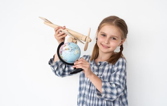 Little girl flying plane model around small globe