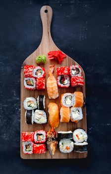 Colorful sushi maki set on wooden desk served with ginger and wasabi. Oriental japanese healthy diet with seafood