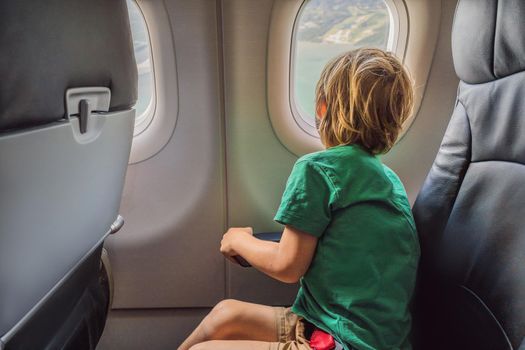 Little boy play with toy plane in the commercial jet airplane flying on vacation.