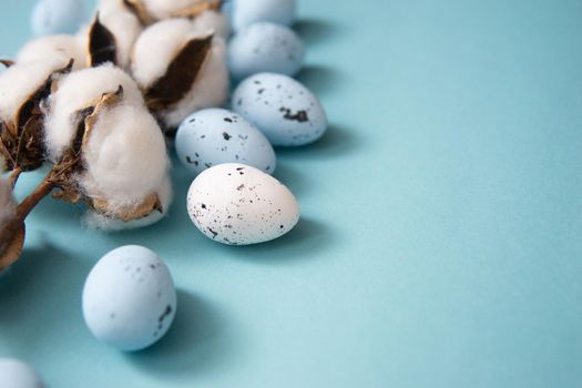 Easter background. Blue and white painted quail eggs on a blue background, decorated with cotton. Happy Easter holiday.