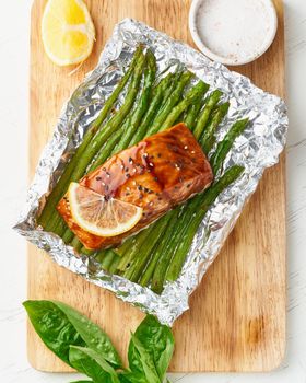 Foil pack dinner with fish. Fillet of salmon with asparagus. Healthy diet food, keto diet, Mediterranean cuisine. Oven-baked hot dinner. Top view, vertical