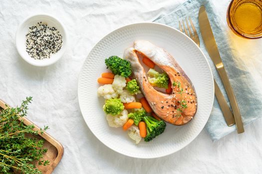 Steam salmon and vegetables, top view. Paleo, keto, fodmap, dash diet. Mediterranean diet with steamed fish. Healthy concept, white plate on gray table, gluten free, lectine free