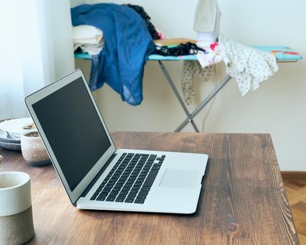 Freelance Desk with laptop in mess at home apartment. Quarantine, self-isolation, sociophobia. Online learning, teleworking, online lectures. Concept of digital nomads, home office