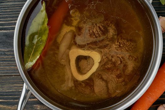Paleo bone broth diet, beef meat soup. Low-carb food, keto recipe. Rich broth of slow languishing on beef and bones, prolonged boiling. Long cooking in pan, macro, close up