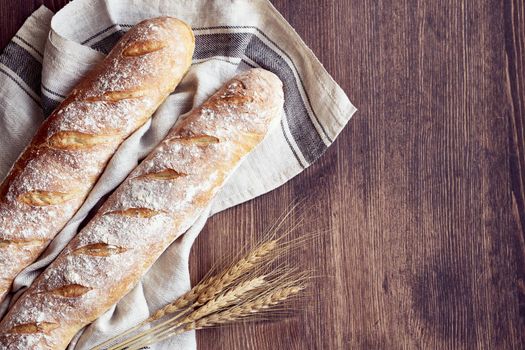 Fresh baked homemade crusty bread baguette. Two loaves on linen towel on wooden table. Delicious and healthy homemade cakes. Copy space