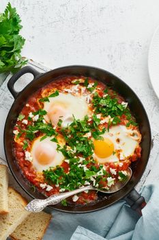 Shakshouka, eggs poached in sauce of tomatoes, olive oil, peppers, onion and garlic, Mediterranean cousine. Keto meal, FODMAP recipe, low carb. Top view, vertical