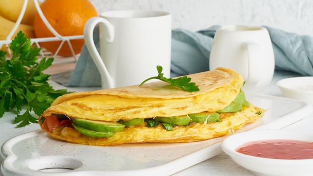 Trendy breakfast with whole quesadilla and eggs, trending food with omelet, cheese, peppers, tomatoes, avocado. Simple and easy lunch, side view