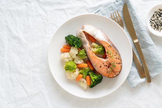 Steam salmon and vegetables, top view, copy space. Paleo, keto, fodmap, dash diet. Mediterranean diet with steamed fish. Healthy concept, white plate on gray table, gluten free, lectine free