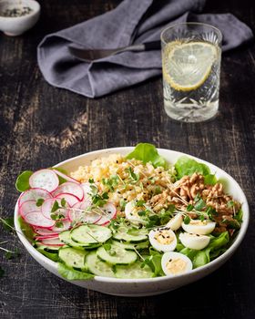 Buddha bowl, balanced food, vegetarian menu, dash diet. Dark wooden table. Eggs, lettuce, bulgur, radish, cucumber, walnut. Vertical