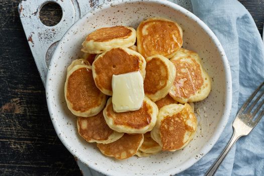 Pancakes cereal, tiny thin funny crumpet, children's food. Breakfast with drink, dark table, bright morning, top view,