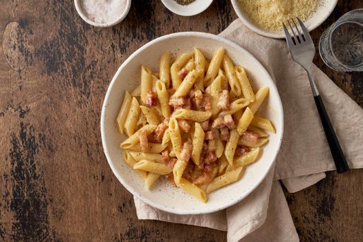 Carbonara pasta. Penne with pancetta, egg, parmesan cheese and cream sauce. Traditional italian cuisine. Top view, copy space