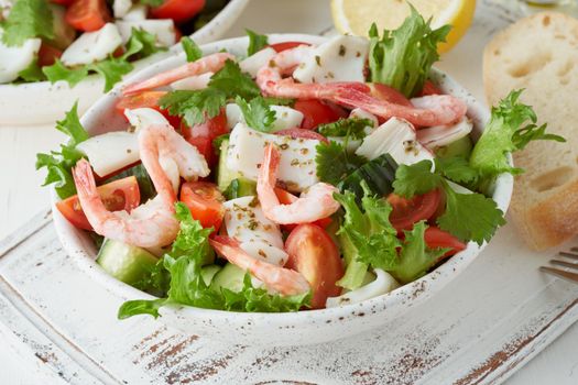 Seafood salad with squid, shrimp, cucumbers, tomatoes and lettuce. LCHF, FODMAP, paleo diet. Fresh spring vitamin mix. Healthy Mediterranean food, balanced food. Side view, close up
