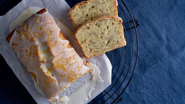 Lemon cupcake with poppy seeds. Traditional homemade cakes. Lemon bread with sugar icing on a dark blue background. Long banner