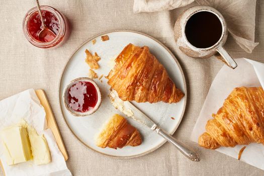 Two delicious croissants and hot drink in mug. Morning French breakfast with fresh pastries and jam. Light gray background, top view