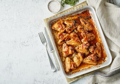 Barbecue chicken wings. Sticky asian spicy wings with teriyaki. Oven baked marinated chiken in metalic tray. Gray table, top view, copy space.