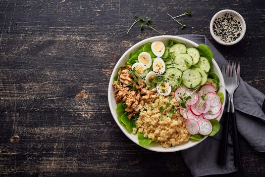 Buddha bowl, balanced food, vegetarian menu, dash diet. Dark wooden table. Eggs lettuce bulgur radish cucumber walnut. Copy space