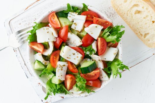 Salad with squid, cucumbers, tomatoes and lettuce. LCHF, FODMAP, paleo diet. Fresh spring vitamin mix. Healthy Mediterranean food, balanced food. Top view