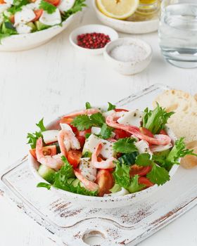 Seafood salad with squid, shrimp, cucumbers, tomatoes and lettuce. LCHF, FODMAP, paleo diet. Fresh spring vitamin mix. Healthy Mediterranean food, balanced food. Vertical, side view