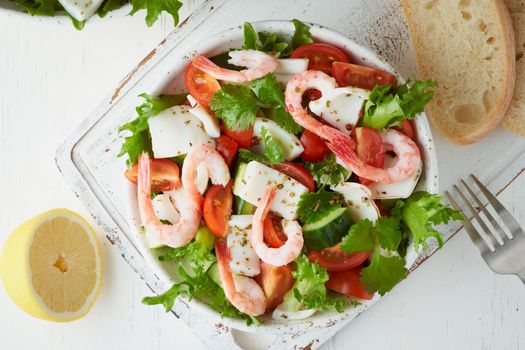 Seafood salad with squid, shrimp, cucumbers, tomatoes and lettuce. LCHF, FODMAP, paleo diet. Fresh spring vitamin mix. Healthy Mediterranean food, balanced food. Top view