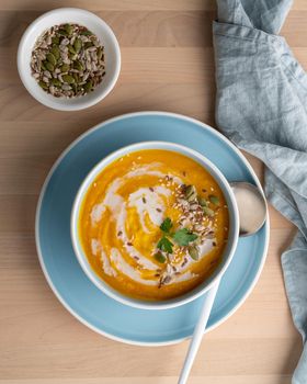 Pumpkin soup with coconut milk, vegetarian dish, healthy and dieting food on wooden background, top view, vertical
