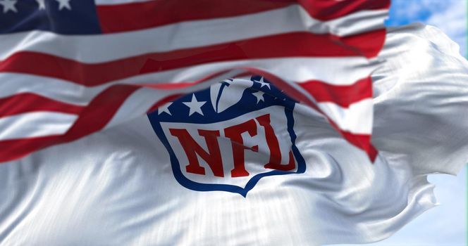 Inglewood, CA, USA, January 2022: The flag with the NFL logo waving in the wind with the US national flag blurred in the foreground. NFL is a professional American football league