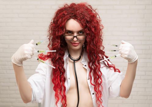 the sexy portrait of a nurse girl with vaccination syringes in her hands