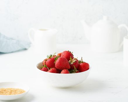 Strawberries in white bowl, on white table, morning Breakfast, summer food, light background