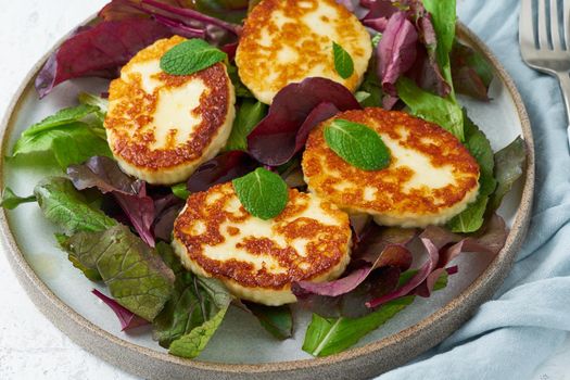 Cyprus roasted halloumi with salad mix, beet tops. Lchf, pegan, fodmap, paleo, scd, keto, ketogenic diet. Balanced food, clean eating recipe. White background, side view