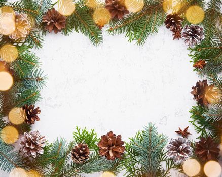 Christmas and Happy New Year light white background. Frame with garland lights, fir branches, berry, cones. Stone backdrop with copy space.