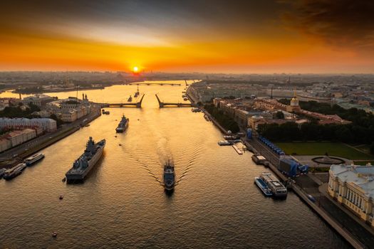 Aerial landscape with warships in the Neva River before the holiday of the Russian Navy at early morning, warships pass under a raised drawbridge, the latest cruisers among landmarks, Palace bridge. High quality photo