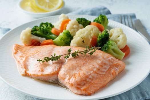 Steam salmon and vegetables, Paleo, keto, fodmap, dash diet. Mediterranean diet with fish. Healthy concept, white plate on gray table, gluten free, lectine free, side view, close up