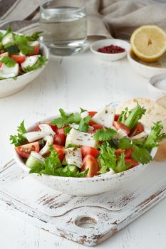 Seafood salad with squid, shrimp, cucumbers, tomatoes and lettuce. LCHF, FODMAP, paleo diet. Fresh spring vitamin mix. Healthy Mediterranean food, balanced food. Vertical, side view