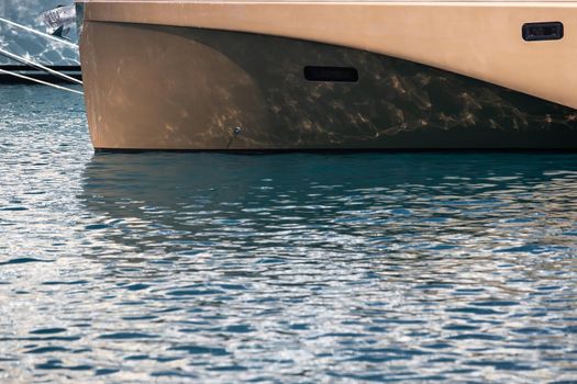 The mesmerizing reflection of the water on the glossy side of a huge yacht anchored, chrome details. High quality photo