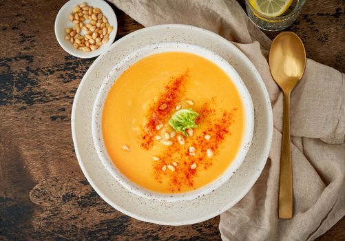 Autumn pumpkin soup with smoked paprika, pine nuts, vegetarian dish, healthy and dieting food on dark background, top view