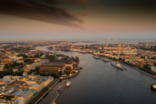 Aerial morning cityscape with warships in the waters of the Neva River before the holiday of the Russian Navy at sunrise, shipyard cranes in the background, cable-stayed bridge, embankment. High quality 4k footage