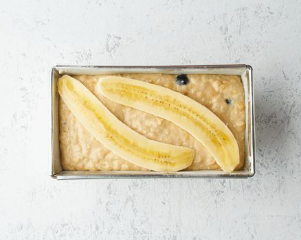 Homemade Banana bread. Dough for cake in pan loaf. Step by step recipe. Step 11. Top view, white table.