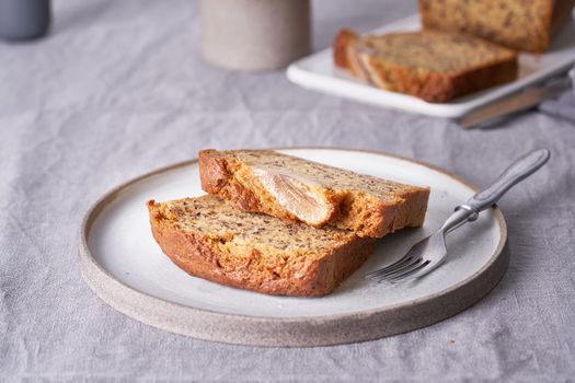 Banana bread. Cake with banana, traditional american cuisine. Slices of loaf. Dark background, black table, shadows. Side view, close up.