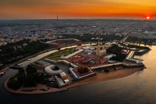 The Peter and Paul Fortress at sunrise, reflection of the orange and pink sky on the water, drawbridges Troitsky and Liteiny are separated. High quality photo