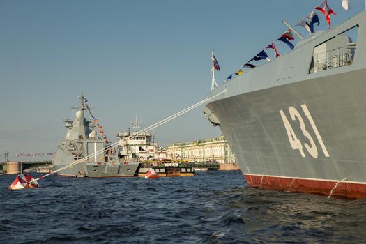 The landscape with warships in the Neva River before the holiday of the Russian Navy at sunny day, the latest cruisers among landmarks, Palace bridge. High quality photo