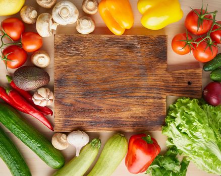 Vegetables around wooden cutting board on kitchen table. Top view, copy space. Menu, recipe, mock up, banner. Food ingredient background.