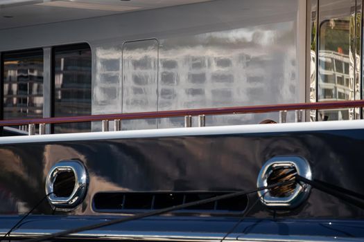The top deck of a huge yacht at sunny day, glossy board of the boat, The chrome plated handrail, megayacht is moored in port, sun reflection on glossy board. High quality photo