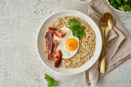 Oatmeal, fried egg, fried bacon. Hearty fat high-calorie breakfast, source of energy. Balance of proteins, fats, carbohydrates. Balanced food. Intuitive conscious food, top view, copy space