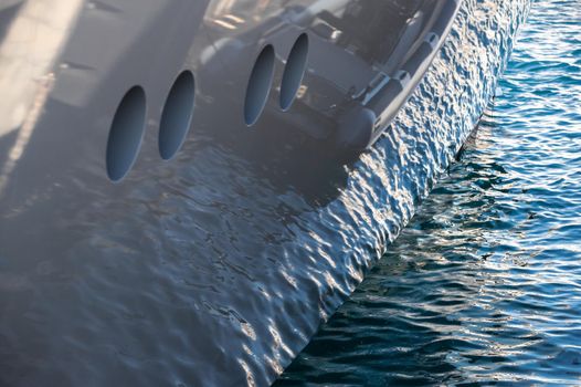 The mesmerizing reflection of the water on the glossy side of a huge yacht anchored, chrome details. High quality photo
